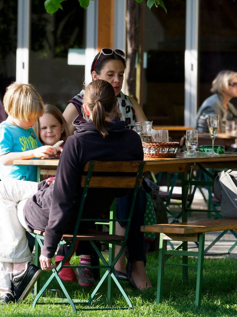 Gäste an langen Tischen im überdachten Teil des Gastgartens