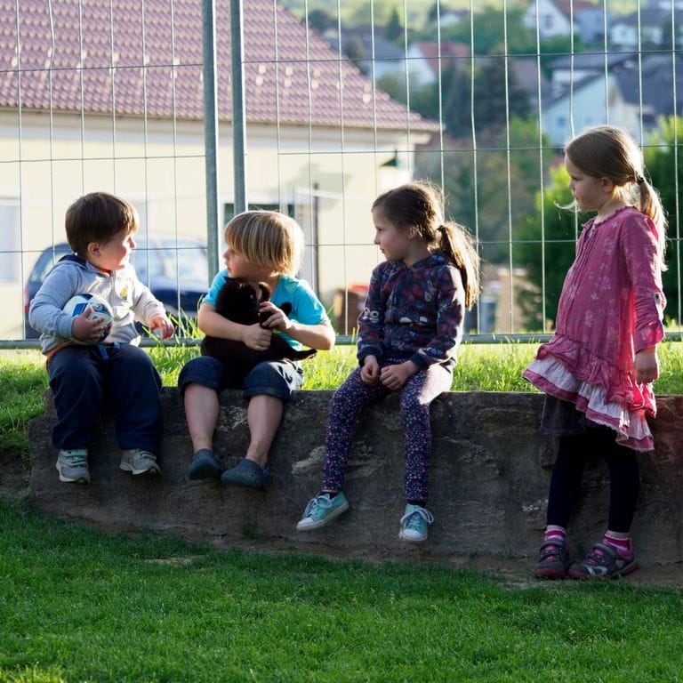 Eine Runde Gäste beim Wein an einem Tisch im Garten